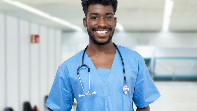 Nurse in scrubs smiling with a stethoscope while enrolled in one of the fastest RN to BSN programs