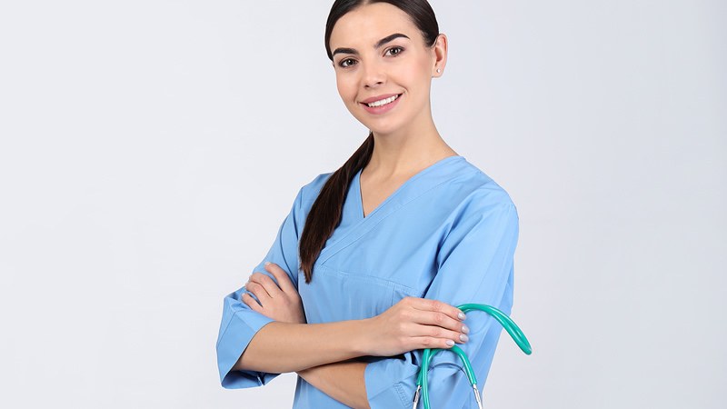 Nurse in scrubs smiling confidently, representing a student in an LPN to RN bridge program.