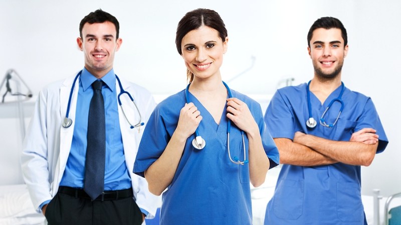 Three nurses standing and smiling in scrubs after completing an ABSN program
