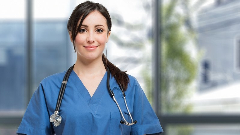 Nurse in blue scrubs with a stethoscope, part of a 2-semester LPN to RN program in a clinical setting.