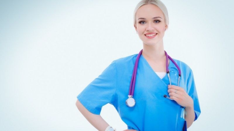 Female nurse in blue scrubs smiling with stethoscope around her neck, representing affordable WHNP programs for aspiring women's health practitioners.