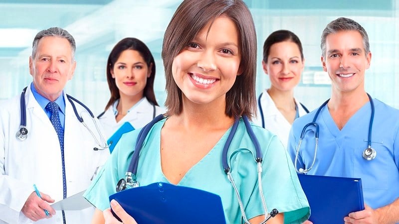 Group of healthcare professionals in scrubs and lab coats smiling in a clinical setting, representing Medical Assistant programs in Miami.