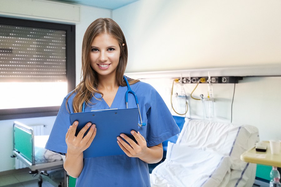 Nebraska nursing student standing inside a hospital with a clipboard.