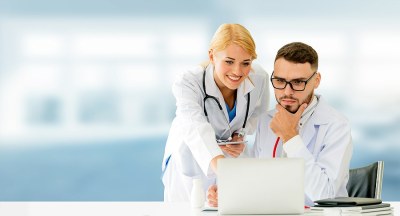 Two nurse informaticists in Alabama reviewing patient data on a laptop in a clinical setting, representing nursing informatics programs in the state.