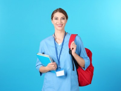 Nursing student in scrubs with books and a backpack, preparing for an associate nursing program in Missouri.