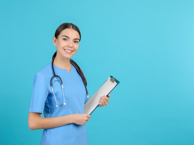 Smiling BSN student in Maryland standing and holding a clipboard.