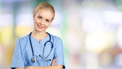 Smiling nurse practitioner student in North Carolina wearing scrubs and stethoscope in a clinical training setting.