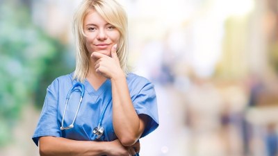 Nurse practitioner student in Michigan standing confidently in scrubs on a university campus.