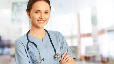 A nursing student in scrubs smiling with their arms crossed while enrolled in a nursing school in Pennsylvania..