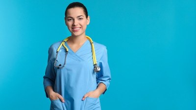 Nurse smiling in scrubs with a stethoscope while completing a 6-month RN to BSN program online