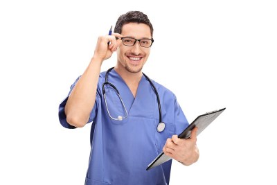 Nursing student in Michigan smiling in scrubs and holding a clipboard.