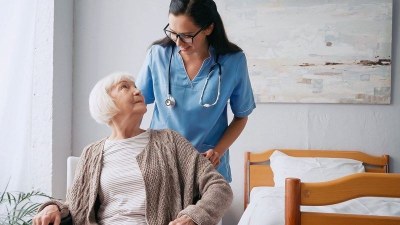 Nurse practitioner student in an affordable AGNP program assisting an older adult in a care setting.