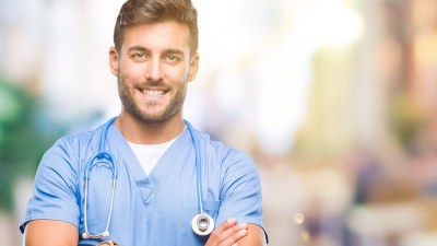 Smiling nurse in scrubs featured in a guide to New York NP programs for future nurse practitioners.