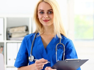 Nursing student in scrubs holding a clipboard at a nursing school in Sacramento, California
