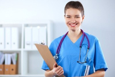 Nursing student in blue scrubs holding a clipboard at a nursing school in Los Angeles, California