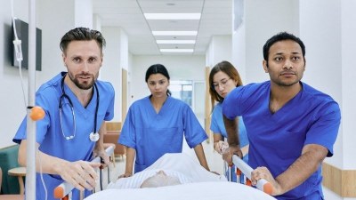 Emergency NP team transporting patient on stretcher in hospital corridor