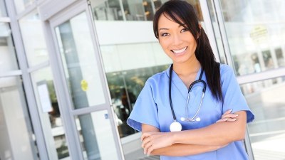 Nurse in scrubs smiling with arms crossed after finishing one of the shortest RN to MSN online programs