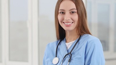 Smiling nurse in scrubs enrolled in an affordable MSN program