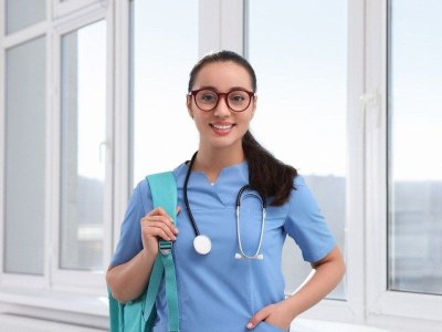 Nursing student in scrubs holding a backpack, preparing for classes in a fast ADN program