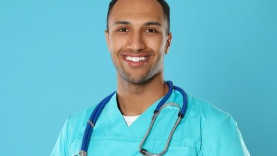 Nursing student wearing scrubs and a stethoscope, smiling while enrolled in the fastest NP program.