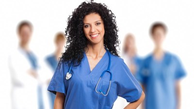 Nurse in blue scrubs with a stethoscope, enrolled in one of the fastest DNP programs, standing in front of a medical team.