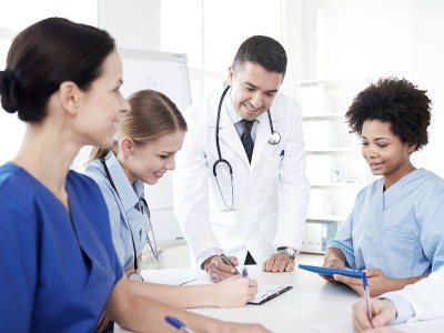 Group of nurses smiling and taking notes in a clinical setting while enrolled in one of the best DNP programs