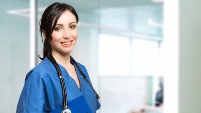 Smiling medical assistant in scrubs standing in a clinical office, representing New Jersey medical assistant programs.