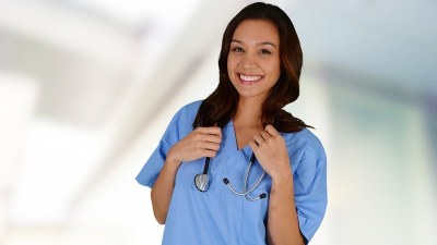 Smiling nursing student in scrubs with stethoscope at a nursing school in Colorado.